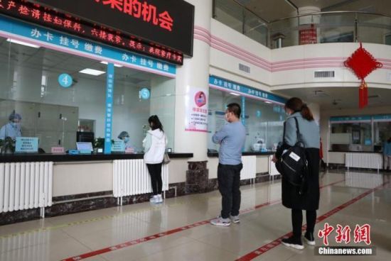 资料图：市民在医院门诊大厅间隔排队挂号。中新社记者 杨迪 摄