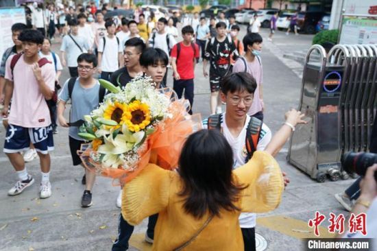 资料图：6月8日，广西南宁第二十九中学考点外，考生家长捧着花与考生拥抱。陈冠言 摄