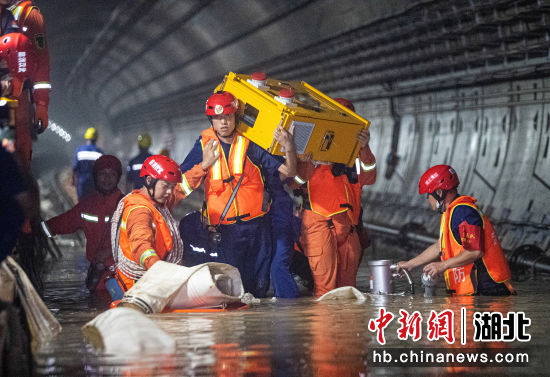 7月26日，在郑州地铁5号线河南省人民医院站隧道内，湖北武汉消防指战员搬运抽水发电设备。艾诗洋 摄