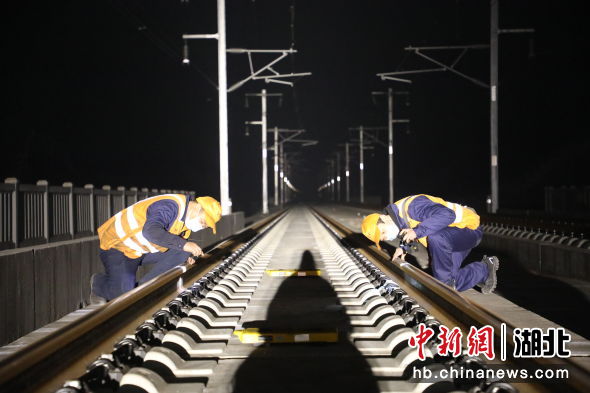 图为武汉大型养路机械运用检修段工作人员夜间检查打磨后的线路质量（杨黎君 摄）