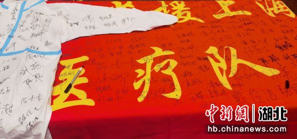 2022年5月30日离开上海国博方舱之前，协和东西湖医院援沪医疗队在队旗和防护服上签名